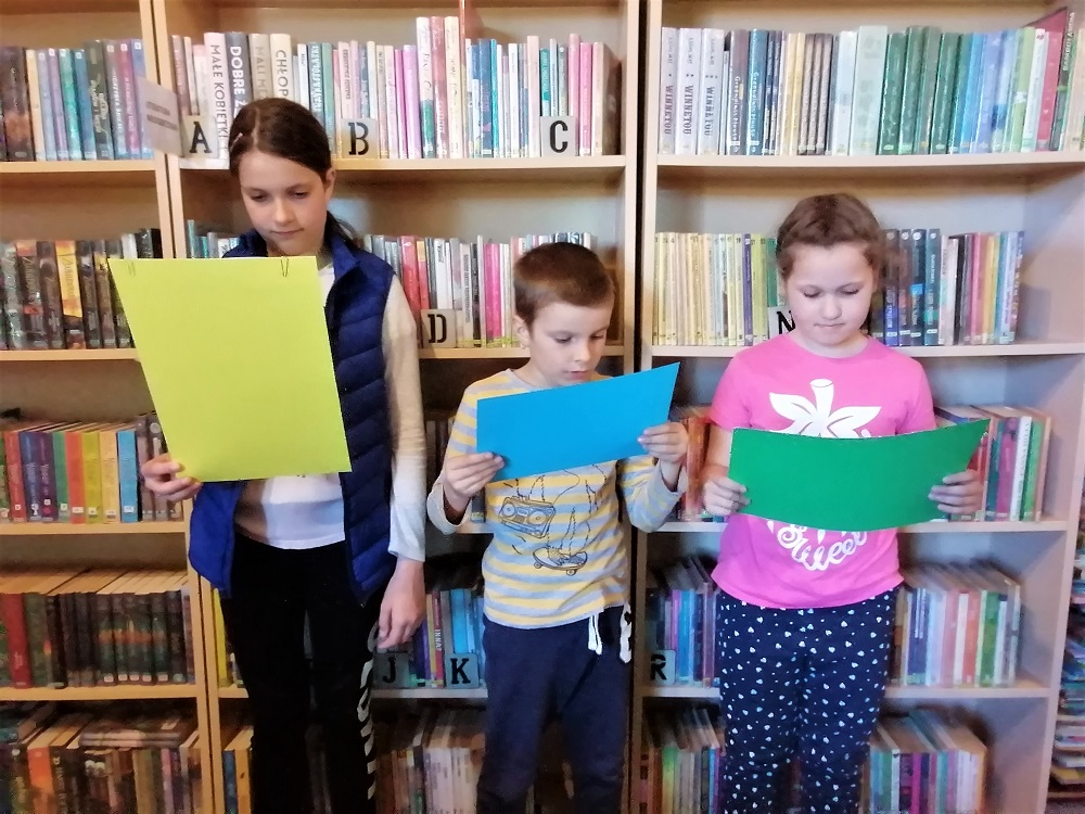 Dzieci czytają wiersze z kolorowych kartek.