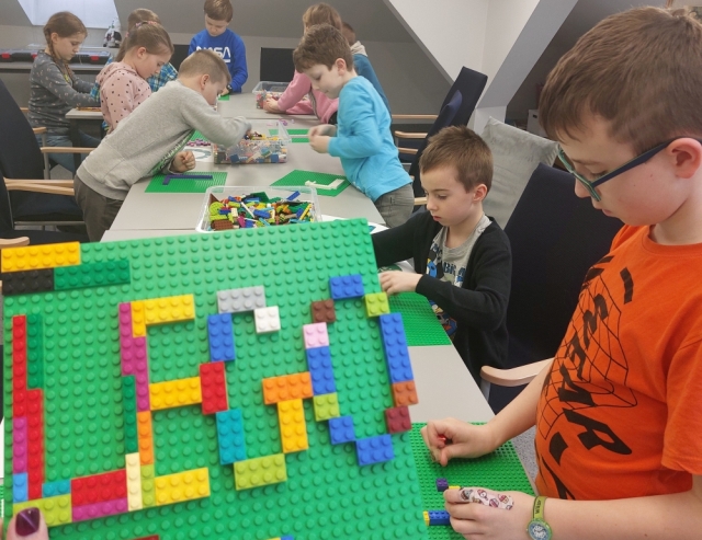 Napis Lego i dzieci budujące z klocków