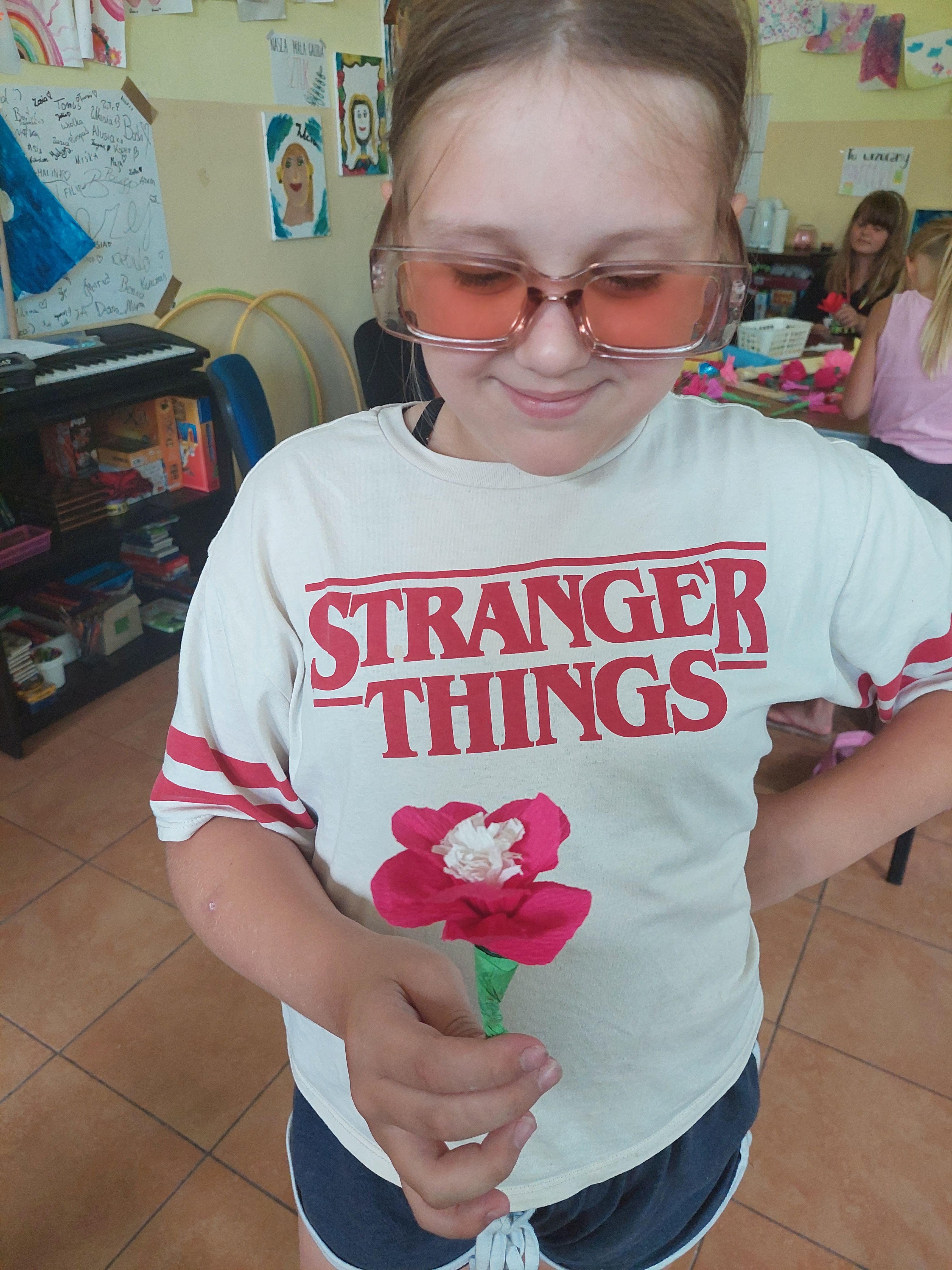 Dziewczynka prezentuje kwiatka z bibuły 