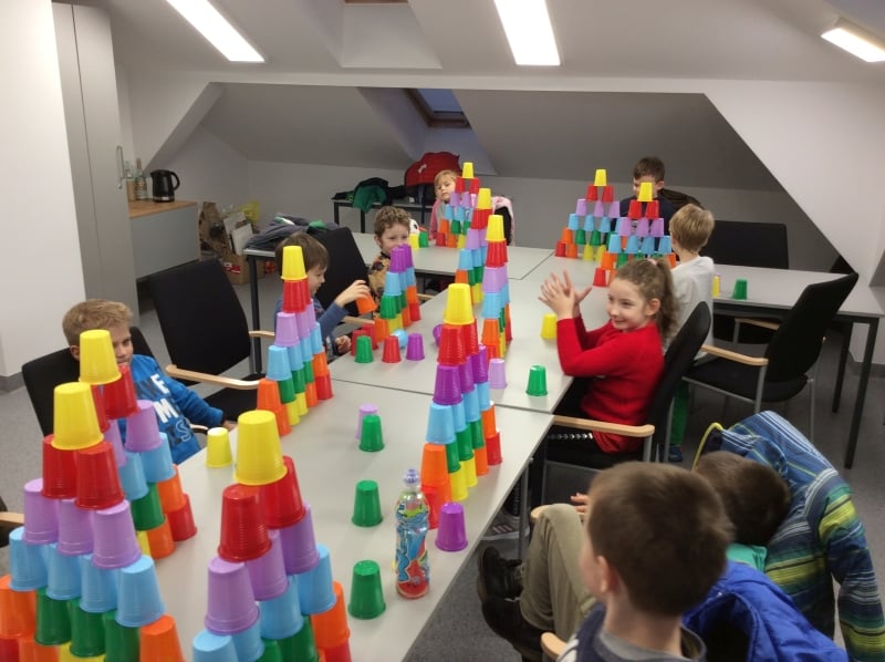 Grupa dzieci buduje wieże z kolorowych kubeczków