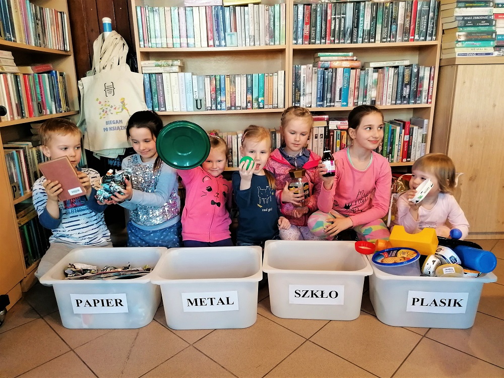 Dzieci segregują śmieci do pojemników.