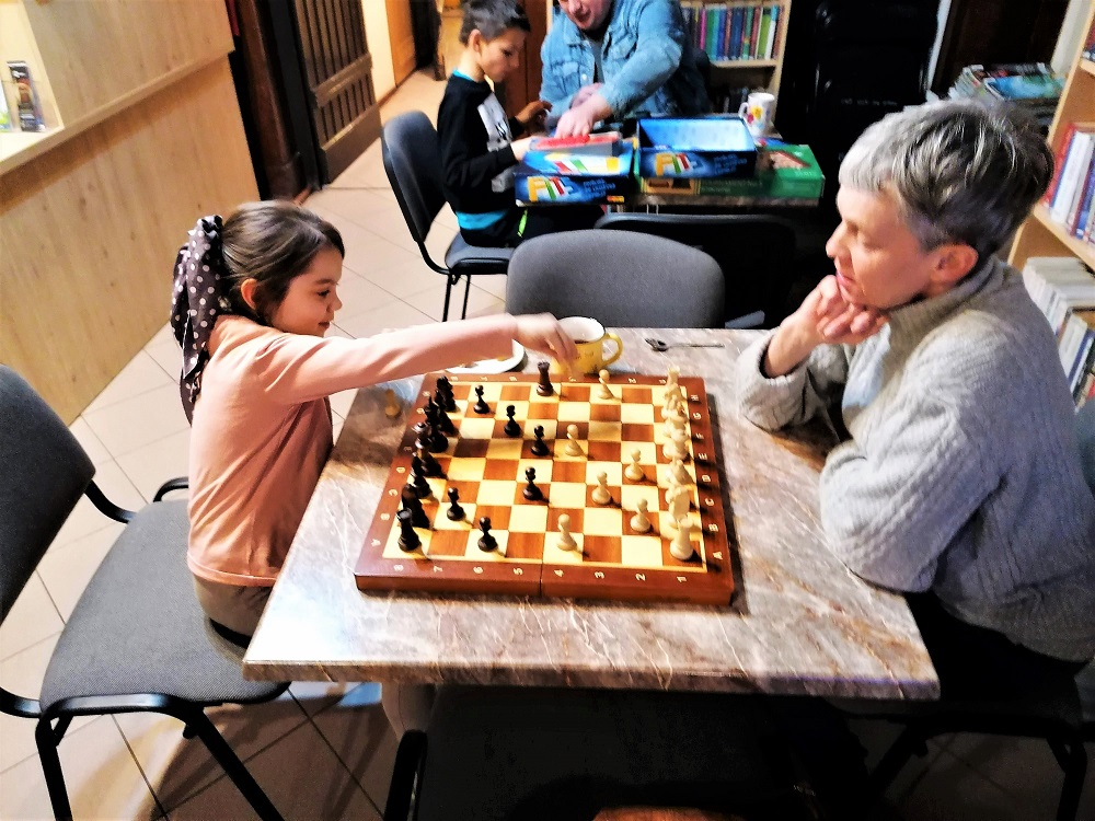 W pierwszym planie instruktorka gra z młodą szachistką.
