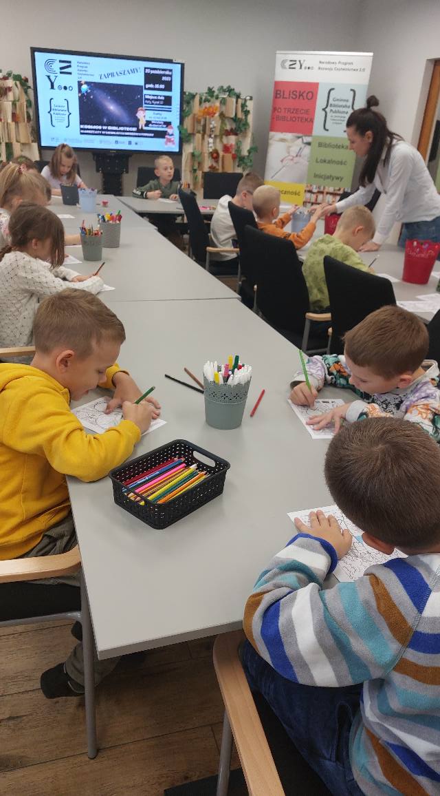 Dzieci malują z zapałem przy stolikach