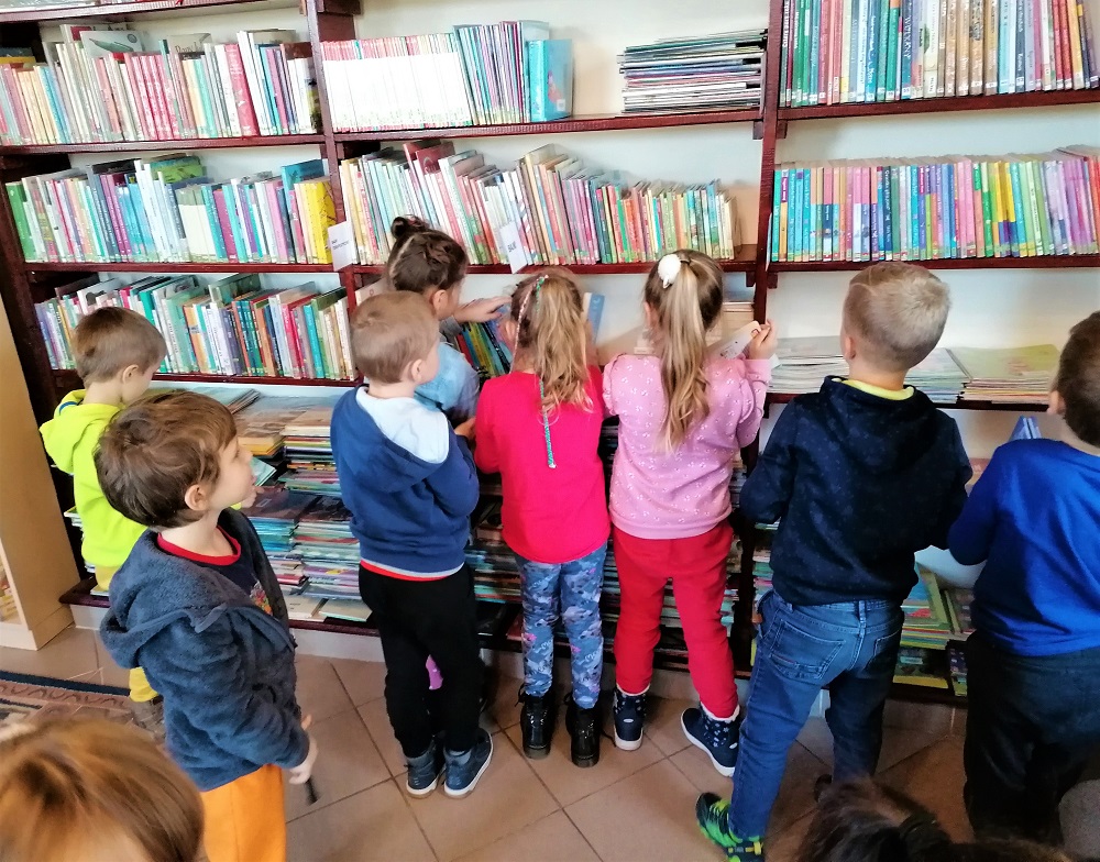 Dzieci samodzielnie układają książki na półkach.