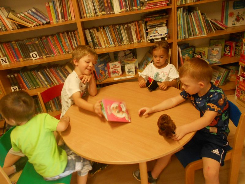 Uczestnicy zajęć siedzący przy stole podczas czytania książeczki o strusiu 