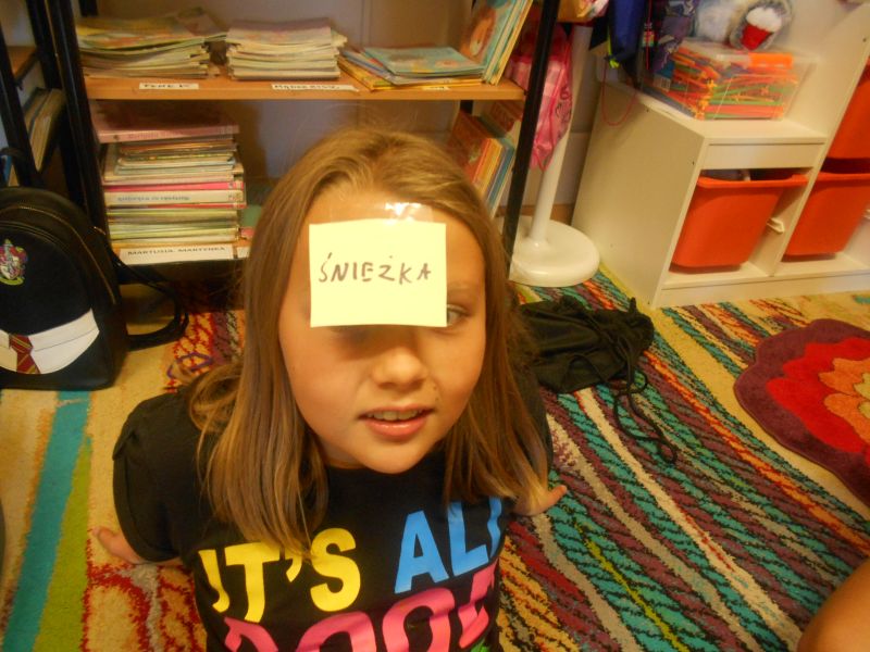 Dziewczynka z karteczką na czole i napisie Śnieżka - gra pt. Kim jestem